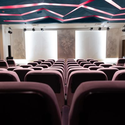 The interior of an empty concert hall with colored lighting and soft seats.